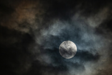 full moon in the midnight behind the cloudy sky