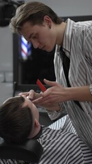 Professional barber trimming customer's hair with electric clipper, focusing on precise nape...