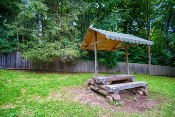 recreation area in a forest, gazebo with a bench and table in the middle of a forest in a clearing