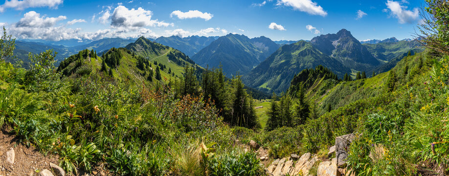 Panorama: Der Berg Widderstein steht dominant am Ende des Kleinwalsertal, mit dem Arlberg im Hintergrund, im Sommer Wander- und Klettergebiet