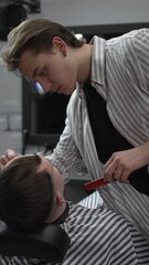 Professional barber trimming customer's hair with electric clipper, focusing on precise nape...