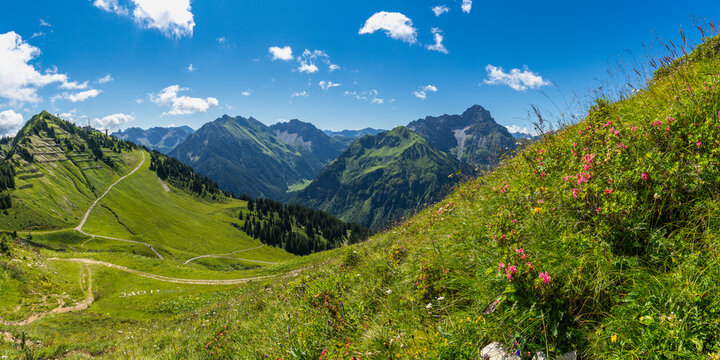 Panorama: Der Berg Widderstein steht dominant am Ende des Kleinwalsertal, mit dem Arlberg im Hintergrund, im Sommer Wander- und Klettergebiet
