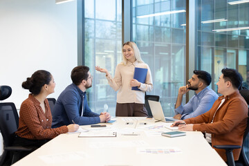 A diverse group of business professionals are collaborating in a modern office setting during a meeting.
