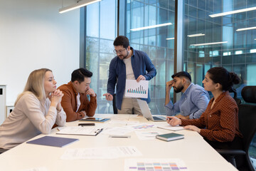 An angry boss confronts colleagues during a tense meeting in a modern office setting, presenting...