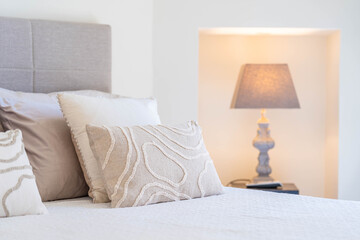 Cozy bedroom with decorative pillows and warm bedside lamp — elegant minimalist interior design for luxury living