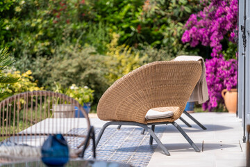 Obraz premium Stylish outdoor lounge chairs on sunny terrace with vibrant bougainvillea — luxury Mediterranean garden living
