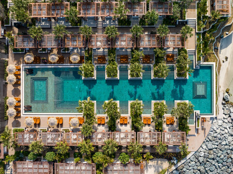 Dubai, United Arab Emirates - 22 February 2025: Aerial view of luxurious beachfront resort, where turquoise waters meet the structured geometry of thatched umbrellas and verdant landscaping.