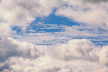 Light clouds curl, revealing a view of the blue sky, close-up, light delicate white clouds with a gap of blue sky, cloudy background.