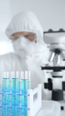 Scientific researcher wearing protective equipment, carefully pipetting liquid into test tubes...