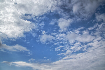 Cloud wisps in the blue sky facing each other, light clouds in the blue sky revealing blue sky in the center of the frame, cloudiness in deep blue sky, blurred background, soft focus.