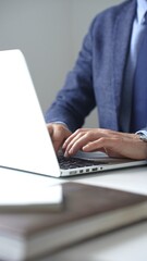 Close up of businessman's hands typing on laptop keyboard, working diligently in a modern office...