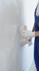 Man construction worker wearing protective gloves and blue construction coveralls, spreading...