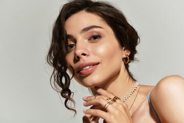 Beautiful young woman showcasing elegant makeup and jewelry in a studio setting