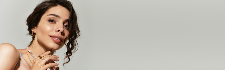 Captivating young woman embracing beauty in a studio setting on a grey backdrop