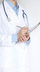 Close up of female doctor wearing stethoscope and white coat over blue blouse is standing and...