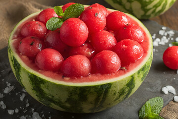 Watermelon fruit balls served in a carved melon, garnished with mint leaves.