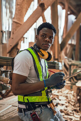 African American Man Working in Timber Factory Performing Quality Inspection on Wooden Planks with...