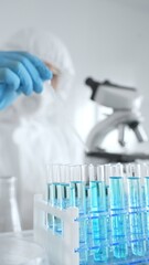 Scientific researcher wearing protective equipment, carefully pipetting liquid into test tubes...