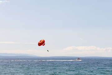Colorful parasail soaring high above the ocean, with a speedboat gliding through the water,...