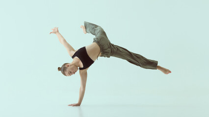 Young woman performing dynamic one-arm handstand in mid-air with confident focus. Concept of...