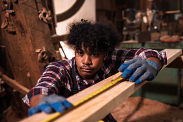 African American Carpenter Measuring Timber Plank in Sawmill, Construction Worker Using Measuring...