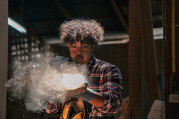 Carpenter Working In Timber Workshop Blowing Sawdust From Wooden Plank Skilled African American...