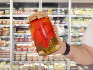 man choosing a can of tomatoes in a supermarket