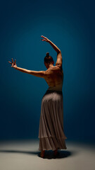 Infinite body. Female contemporary dancer standing in elegant pose with raised arms and long skirt...