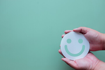 Mental health and well-being concept. Hands holding a smile symbol represents happiness, positive thinking, and emotional support. A sign of a healthy and happy life. Psychology concept.