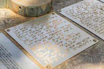 Braille text displayed on metal plaques in sunlight, showcasing tactile reading for visually...