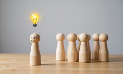 Single wooden pawn with a smiling face stands out with a glowing light bulb symbolizing an idea above