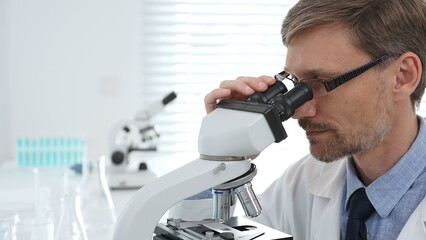 Scientist using a microscope is doing scientific research in a modern laboratory, developing innovative medicine for healthcare. Medicine, healthcare and science concept