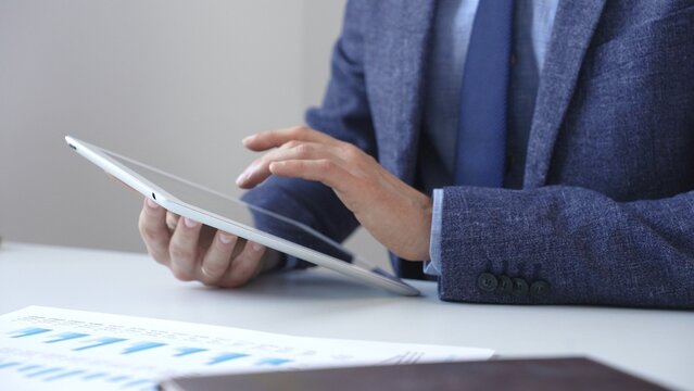 Businessman is using a digital tablet to analyze financial data, working with modern technology in the office for strategic corporate decision making and workflow optimization. Business people concept