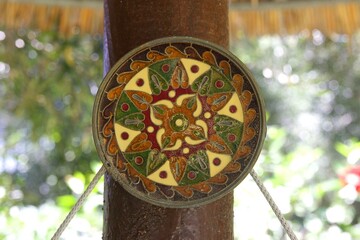 Colorful handcrafted round mandala ornament hanging on wooden pole outdoors
