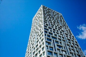 Obraz premium The modern building with a white façade and large windows, reaching upwards against the backdrop of a clear blue sky, creates a feeling of lightness and harmony.