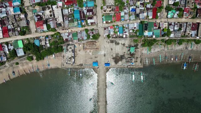Picturesque top-down aerial view of rural barangay village along tropical island coastline at Codon Port, San Andres, Philippines.