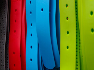Close up of plastic pvc waist belt in red, blue, green. and grey showing the holes,
