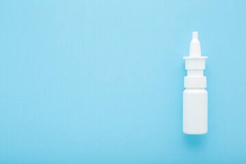 New white plastic spray bottle of medical liquid to stop nose running on light blue table...