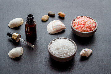 Spa treatment body care cosmetics close up. Sea salt in bowl and essential oil on bottle