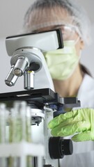Close up of scientific precision involving green gloved hands adjusting microscope lens, blurred...