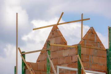 Bricks frame with wooden pole and scaffolding, Construction structure on site work under blue sky and clouds, Rooftop mockup houses building with geometric isosceles triangle shape.