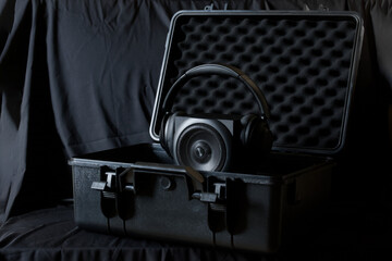 Over‑ear headphones draped on a high‑end speaker inside a rugged foam‑lined case, symbolizing...
