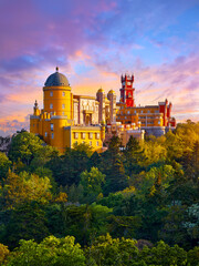 Sintra, Portugal. Palace of Pena in the National park. Lisbon. Sunrise among green trees. Beautiful fairytale castle forest pine-trees. Panoramic summer view at palace. Sunlight clouds on sky.