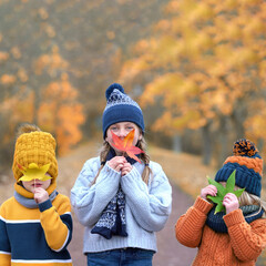 three Kids Hiding Behind Colorful Autumn Leaves
