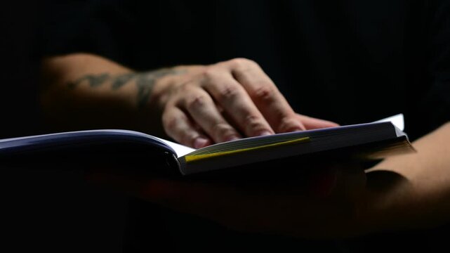 A man reads an interesting book in a dark room and turns the pages with his hand.
A student with a kinga in his hands on a black background.
The concept of learning and self-development