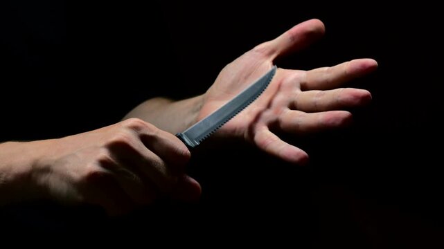 A man in black clothes threatens with a sharp steel knife in a conflict situation.
A man brandishes a sharp knife and intimidates someone.
A criminal with a knife
