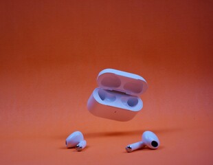 Modern Wireless Earbuds and Charging Case on Bright Orange Background