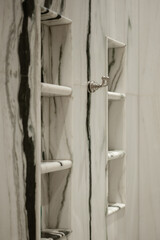 Close-up of built-in shelving and a chrome hook made from luxurious Panda marble with dramatic...