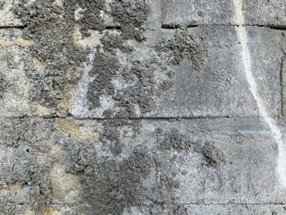 Close-up texture of an old rough concrete wall with uneven cement layers, cracks, and weathered surface details in natural daylight.