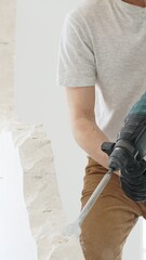 Unknown male construction worker with white t-shirt and protective gloves, is demolishing white...